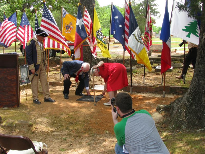Lester Sparks and unidentified ancestor removing cover from marker.